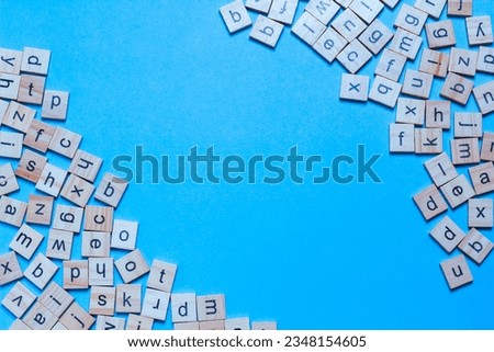 English alphabet made of square wooden tiles with the English alphabet scattered on blue background. The concept of thinking development, grammar.