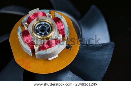 Closeup of electric motor stator with electronic coils and ball bearing on black background. Red copper wire winding and metal ferromagnetic sheets of computer fan electromotor on rotor plastic vanes. Royalty-Free Stock Photo #2348161249