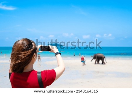 Asian female tourists Taking pictures with a smartphone on Koh Chang , THAILAND