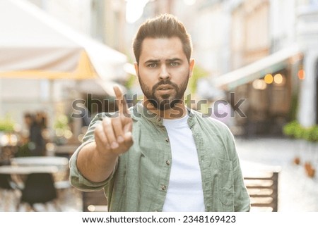 Displeased upset man reacting to unpleasant awful idea, dissatisfied with bad quality, wave hand finger shake head No, dismiss idea dont like proposal. Adult guy standing in urban city street outdoors Royalty-Free Stock Photo #2348169423