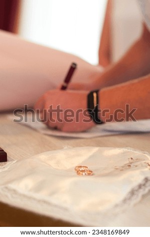 marriage registration, signing documents, wedding rings in the foreground, groom signing papers