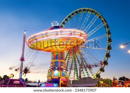 Funfair panorama wiht ferris wheel and carousels on big german funfair “Cranger Kirmes“ in Herne at blue hour twilight. Long time exposure with multi color light traces (“Kasse“ means cash register). Royalty-Free Stock Photo #2348175907