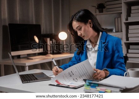 Asian businesswoman search the pile of documents in office at night, working over time concept.