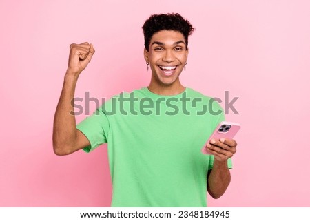 Photo of cool lucky guy wear green t-shirt winning game modern gadget rising fist isolated pink color background