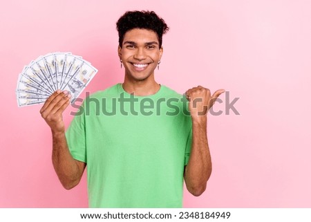 Photo of charming attractive guy wear green t-shirt showing money fan thumb empty space isolated pink color background