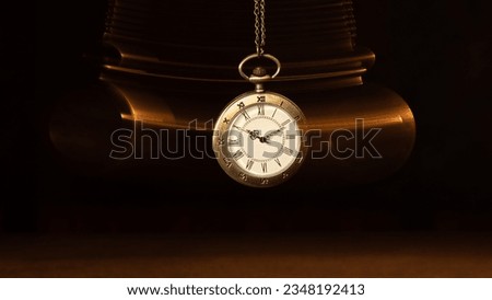 Hypnosis session. Vintage pocket watch with chain swinging over surface on dark background among faded clock faces, magic motion effect Royalty-Free Stock Photo #2348192413