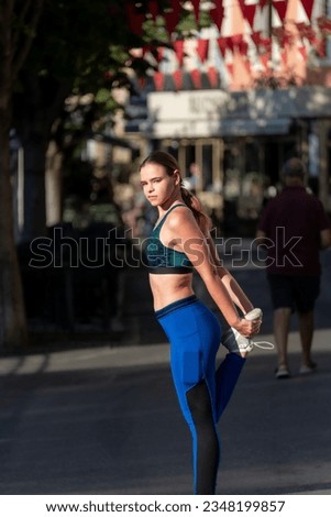young woman stretching in the early morning light in small street ,dressed in sportswear .concept of sports and fitness .