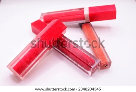 four beautiful lip glosses, isolated on white background,Fuchsia color lip gloss with glitter particles in elegant glass bottle with golden lid, closed and open container with brush and stroke sample,