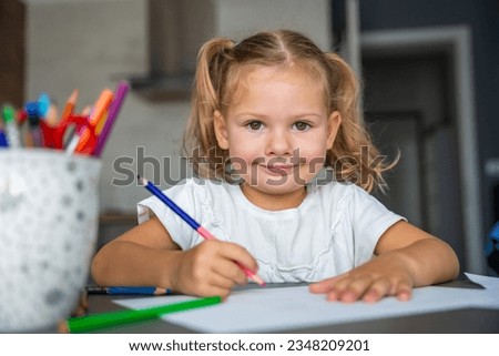 little girl draws with colored pencils in home. High quality photo. 