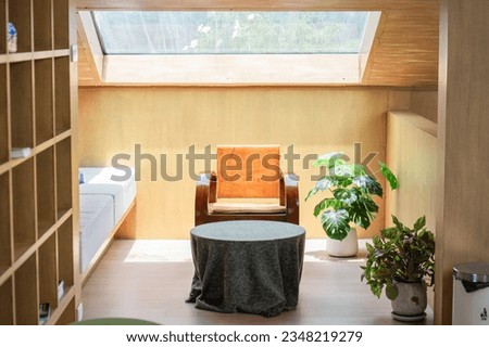 The living room has a skylight that lets in natural light and is furnished with a table, chairs, and various decorative plants. Royalty-Free Stock Photo #2348219279