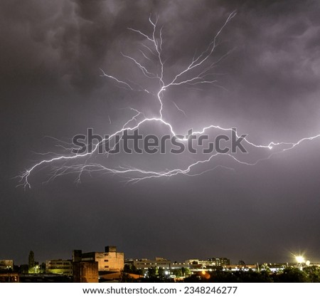 Tree shaped lightning above industrial city area. Night sky with grey clouds over the city. Urban area and electrical discharge. 