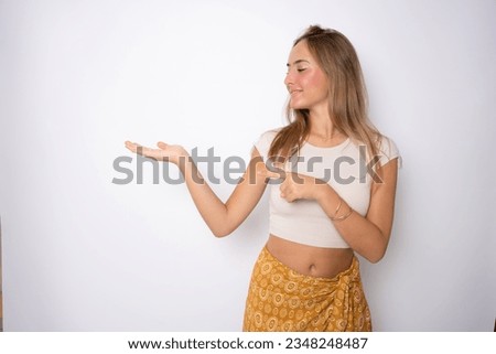 Teenager girl on isolated white wall holding copy space imaginary on the palm to insert an ad