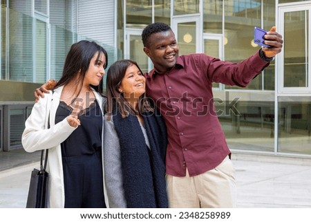 Happy coworkers taking a selfie photo at work break. Group of young friends smiling at office outdoors. Ethnic diversity.