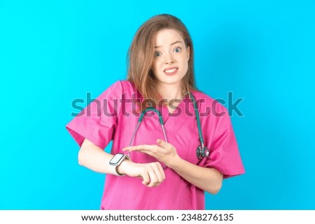 Young caucasian doctor woman wearing medical uniform In hurry pointing to watch time, impatience, upset and angry for deadline delay. Royalty-Free Stock Photo #2348276135