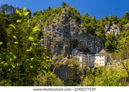 Predjama castle panorama on a sunny summer day. Historic monument was built within a cave mouth in Slovenian Karst landscape. Popular tourist attraction in an idyllic valley near Postojna Caves. 