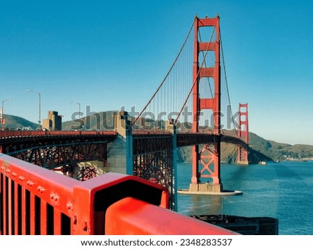 A unique view of the San Francisco Golden Gate Bridge, a suspension bridge spanning the one-mile-wide strait connecting San Francisco Bay and the Pacific Ocean. The sky and water are deep blue.