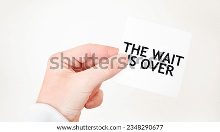 Businessman holding a card with text THE WAIT IS OVER, business concept