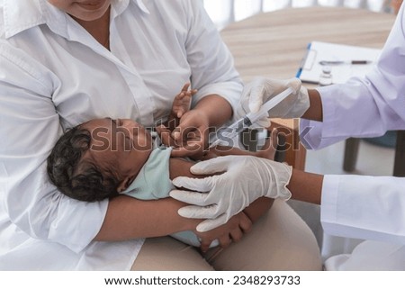 The doctor is vaccinating prevent virus for 1-month-old baby newborn son is half Thai half Nigerian, who is lying on mother's lap, to vaccine for baby and health care concept. Royalty-Free Stock Photo #2348293733
