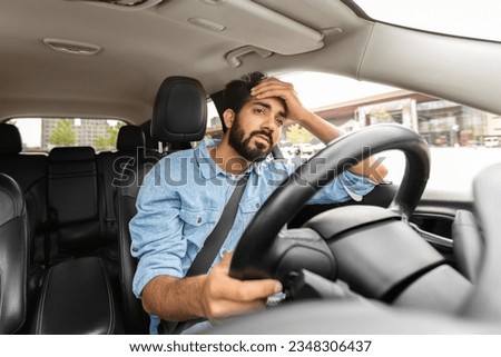 Guy driving car despair after accident. Upset driver, stressful situations on road, fast rhythm in modern city. Sad unhappy tired indian man holding steering wheel in auto, presses hand to his head Royalty-Free Stock Photo #2348306437