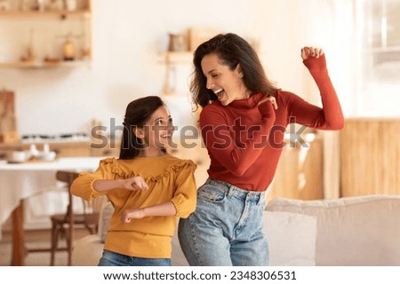 Cheerful Middle Eastern Mother And Daughter Kid Dancing Together At Modern Kitchen Interior. Young Mom And Preteen Child Girl Having Fun During Home Party Indoors On Weekend