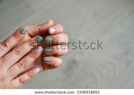 Women's hands with colorful pattern on the nails. Top view. Place for text. Cozy green design.