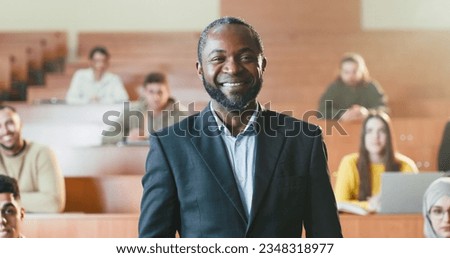 African American male cheerful professor taking selfie photo with smartphone among multiethnic students in auditorium of University. Educator and pupils concept. Making photos with phone.