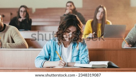 Caucasian beautiful girl reading textbook at lection and asking something guy with laptop. Whispering at seminar in college. University study concept. Female read book at class and talking. Royalty-Free Stock Photo #2348319087