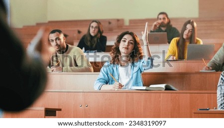 Portrait of young beautiful Caucasian female student sitting at the desk, noting lection and looking at camera. Indoor in classroom. High school concept. Girl studying at University and writing down. Royalty-Free Stock Photo #2348319097