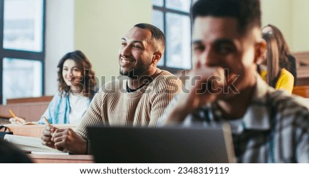 Happy young mixed-races students laughing and talking with professor at lection in University. Guys smiling and talking with teacher at high school. Knowledge getting concept. Multiethnic people. Royalty-Free Stock Photo #2348319119
