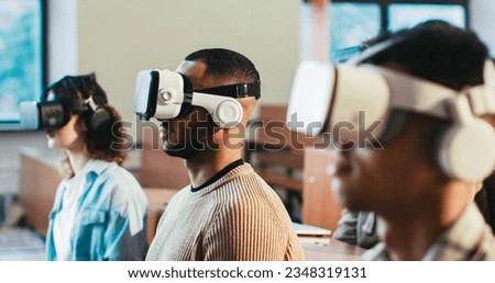 Close up of mixed-races males and female students in VR glasses sitting at college and listening to lection. Hi-tech studying. Multiethnic young people having virtual reality learning experience. Royalty-Free Stock Photo #2348319131