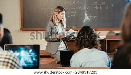 Beautiful Caucasian female professor explaining lection at University in front of students sitting at desks. Education concept. Woman teacher speaking to young adults at college. Geometry math lesson. Royalty-Free Stock Photo #2348319203