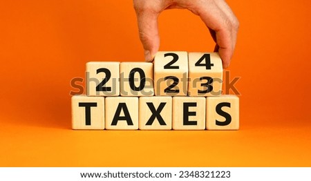 2024 taxes new year symbol. Businessman turns a wooden cube and changes words Taxes 2023 to Taxes 2024. Beautiful orange table orange background, copy space. Business 2024 taxes new year concept.