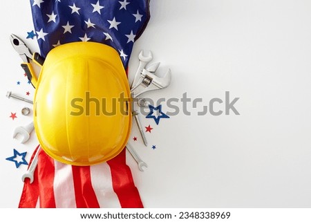 Picturing a vibrant concept for a happy Labor Day celebration. Top view shot of american flag, work hard hat, instruments, stars confetti on white background with empty space for advert or text
