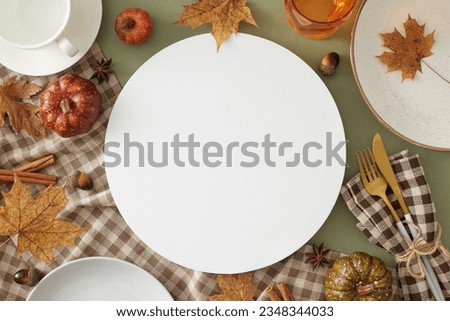 Thanksgiving gathering idea.Top view photo of plates, cutlery, glass, teacup, checkered napkin, tablecloth, autumnal decorations on olive background with blank circle for advert or text