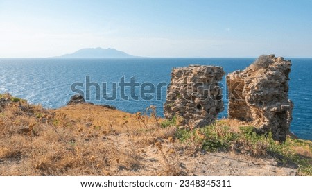Gokceada (Imbros) coastline seashore view with Samothrace Greek island and ruined Kalekoy castle walls at background. Imbros island. Aegean Turkey. Canakkale
