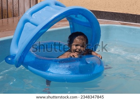 Baby girl with captivating smile in the pool wearing a float