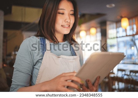 Restaurant, tablet and Asian woman online for order for food service, inventory and check menu. Coffee shop, small business and happy waitress, barista or manager on digital tech for cafe website