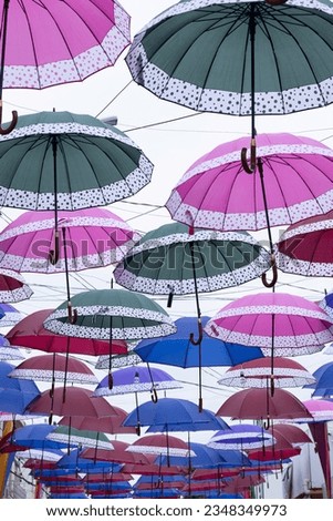 several colorful parasols hanging on a cloudy day