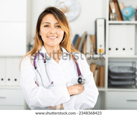 Portrait of confident latina female doctor standing in clinic office Royalty-Free Stock Photo #2348368423