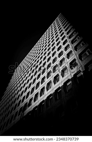 This image is a black and white photograph of a tall, commercial building. The camera angle is low, giving a unique perspective on this structure as it towers above us.