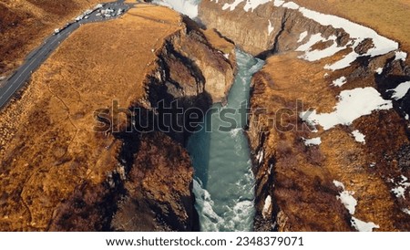 Aerial view of gullfoss river waterfall, beautiful cold water flowing between frozen snowy hills and fields. Icelandic nature and nordic scenery near cascade. Slow motion.