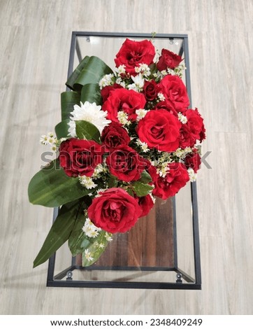 A beautiful bouquet of red roses, white daisies and white chrysanthemums put on a long glass table. Used for gifts or room decoration. Photo from above