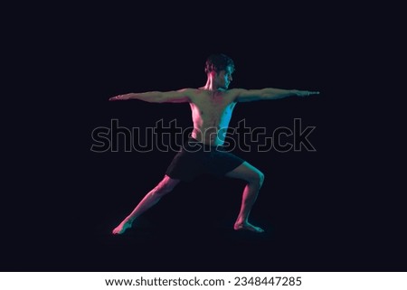 Young male doing yoga asana in dynamic lighting