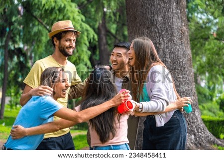 Multiethnic group of birthday party in the city park hugging in a symbol of friendship forever and smiling a lot