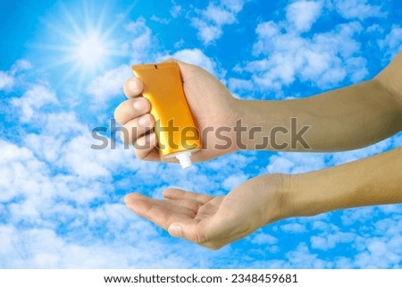 A man is applying sunscreen and skin care to protect her skin from UV rays. he is applying sunscreen on her hand and arm. The sun symbol is a very sunny background. Health and skin care concept Royalty-Free Stock Photo #2348459681