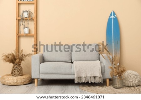 Interior of modern stylish room with surfboard, shelving unit and sofa