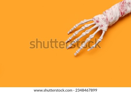 Skeleton hand for Halloween celebration on orange background