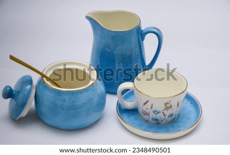 Mock up - design set of elegant and traditional teapot colorful white and blue coffee cup and Tea cup on cup's plate beside the hot tea pot , flowers and butterflies drawn on the ceramic mug cup
