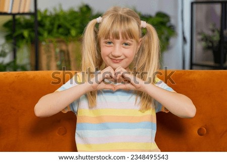 I love you. Child kid girl makes symbol of love, showing heart sign to camera, express romantic feelings, express sincere positive feelings. Charity, gratitude, donation. Female teen toddler at home Royalty-Free Stock Photo #2348495543