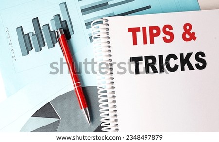TIPS AND TRICKS text on notebook with pen on a chart background